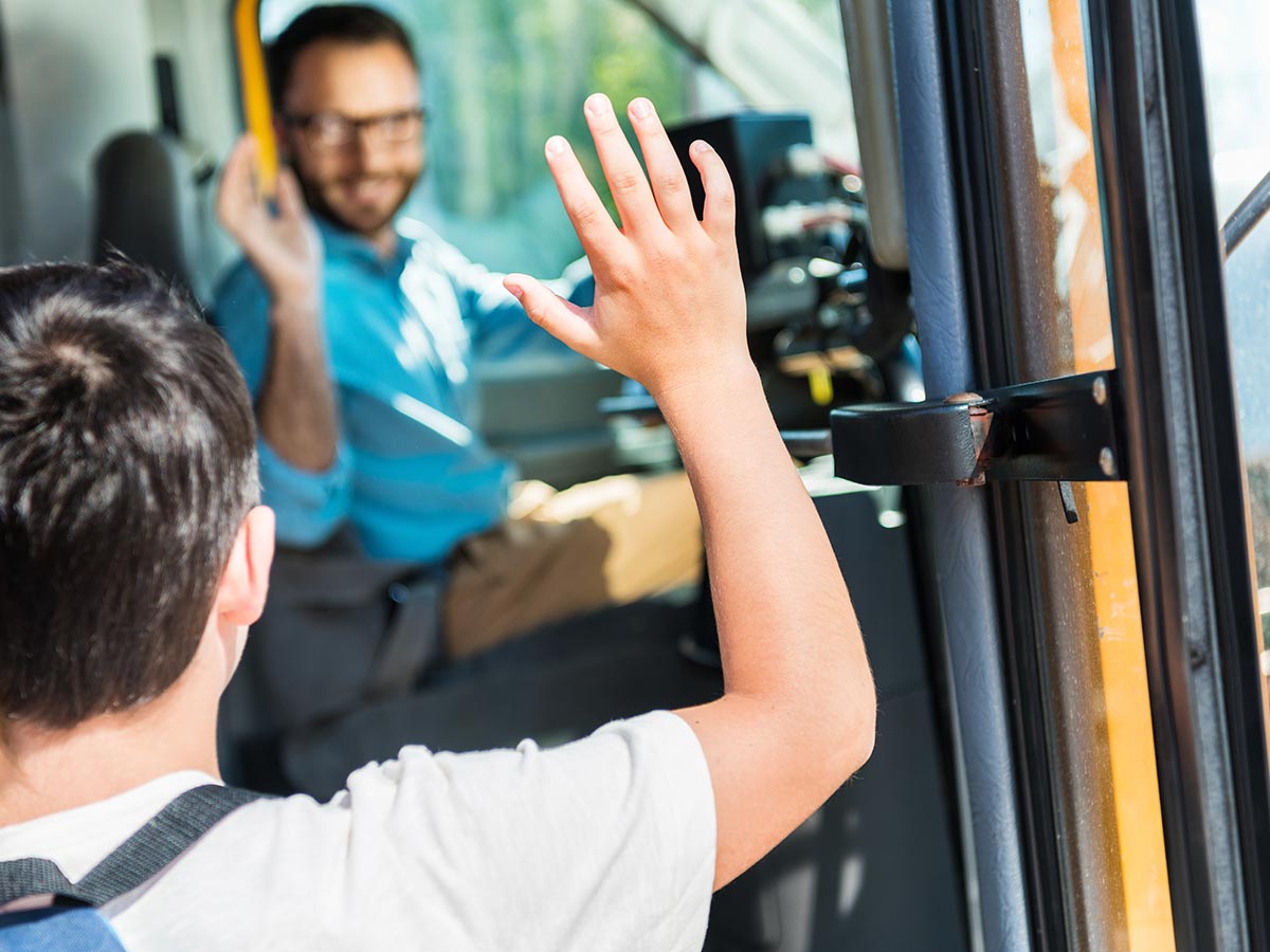 Child boarding bus and saying hi to the bus driver