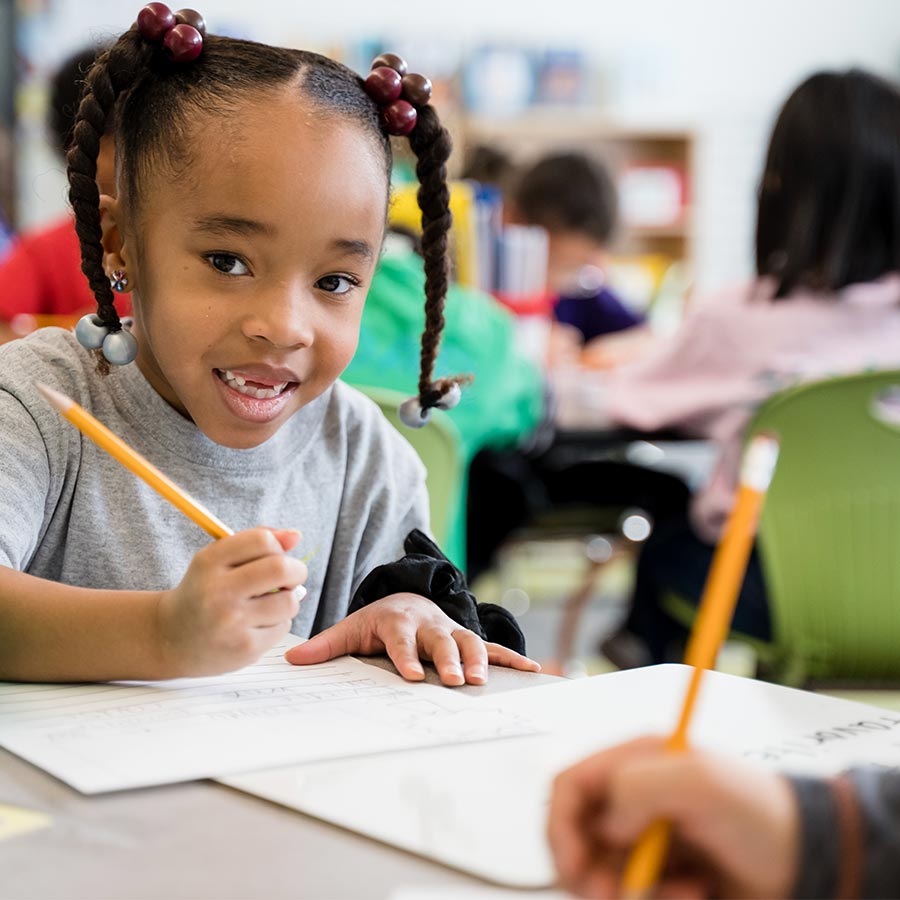 Girl smiling while working on an assignment in the classroom